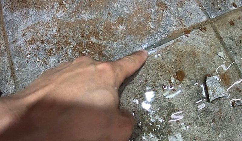 물이 고여 있는 바닥 틈을 손가락으로 가리키는 모습